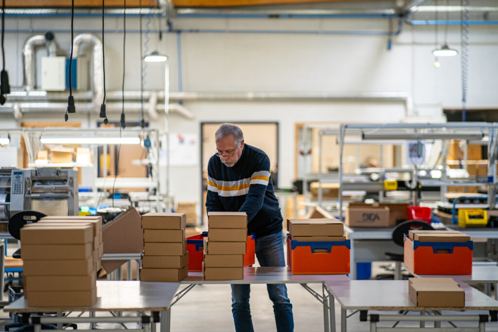 Travailleur en atelier réalisant un kitting et un conditionnement de colis dans le département emballage de l’ETA Le Perron à Liège.
