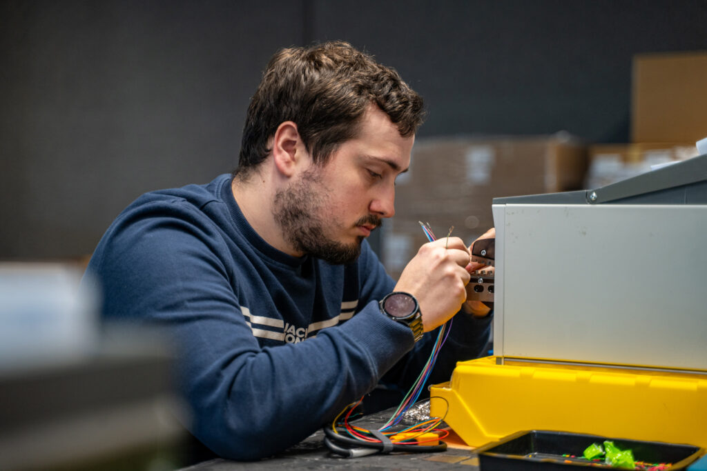 Travailleur en situation de handicap réalisant un câblage électrique dans l’atelier électricité de l’ETA Le Perron à Liège.