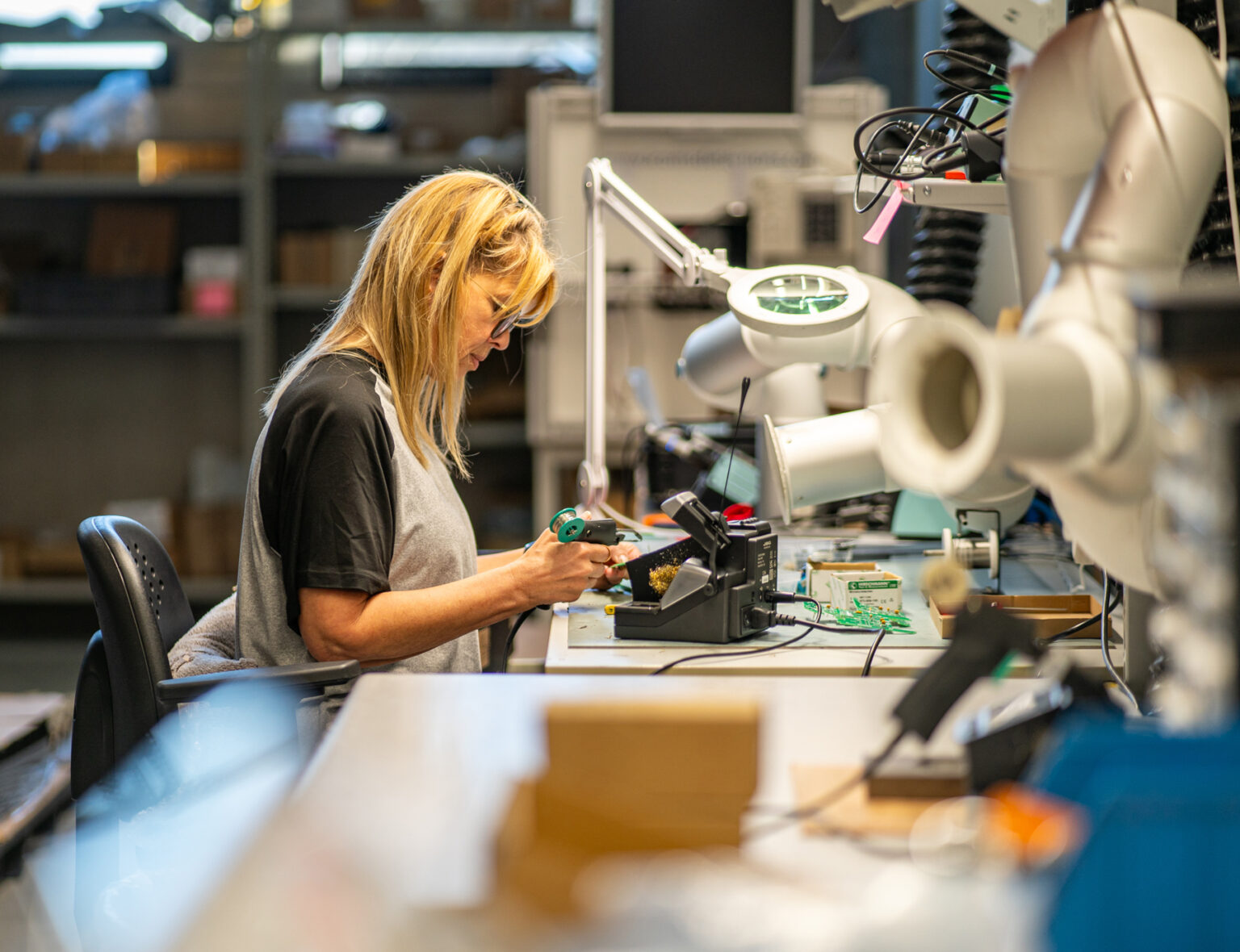Travailleuse en situation de handicap effectuant une opération de soudure électronique dans l’atelier électricité de l’ETA Le Perron à Liège, spécialisée en sous-traitance industrielle.